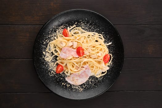 Spaghetti with ham and tomatoes sprinkled with grated parmesan, top view