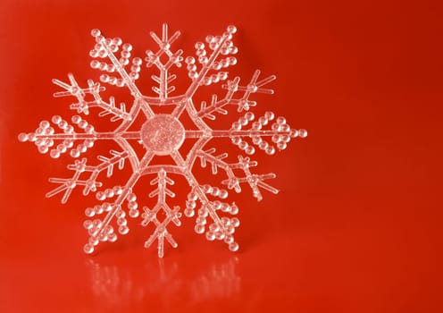 A gluttery snowflake ornament on a red background