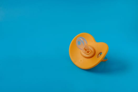 An orange pacifier on a blue background