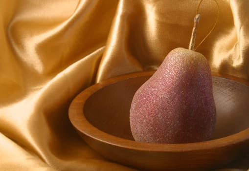 A pear ornament in a wooded bowl