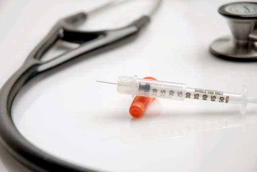 A stethoscope and small syringe  isolated on white