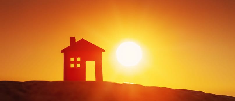 Model of a house standing on the ground on sunset evening. Concept of buying or selling a new appartment.