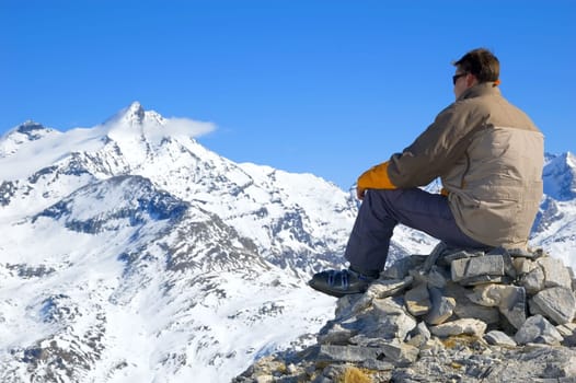 man, sitting on some rocks, looking over a mountain range