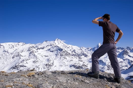 man looking over a mountain range, hand to forehead