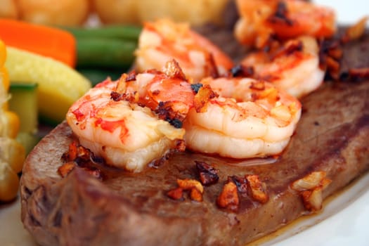 Close up of a steak with garlic butter sauce and fresh king prawns - surf n' turf