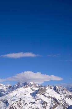 snowed peak of a mountain surrounded by small cloud, a lot of blue for copy-space