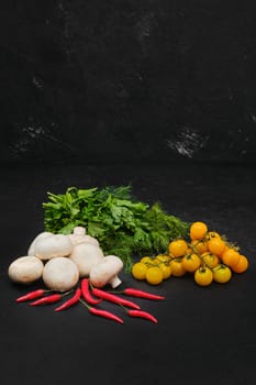 Fresh tomatoes, champignons, dill, parsley and chili on black background