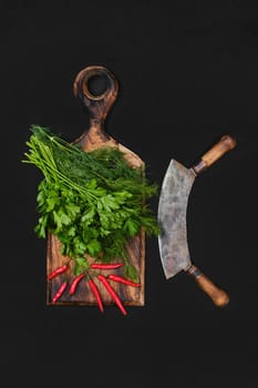 Fresh dill, parsley and chili on black background with mezzaluna knife