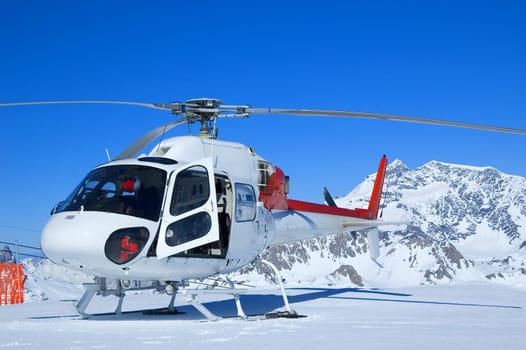 red and white rescue helicopter parked in the mountins