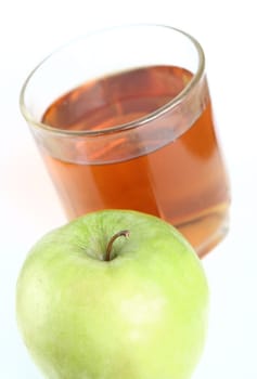 Green apple and glass of juice on a white background