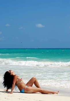 beautiful brunette tanning at white sandy beach