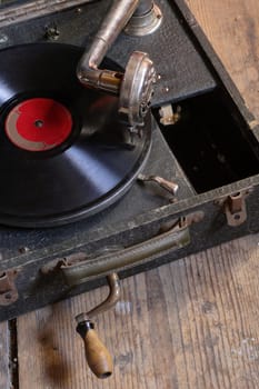 An antique box record player with crank, sitting on the attic floor.