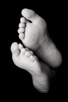 Woman's feet in high key over black. Focus is on the toes of the top foot
