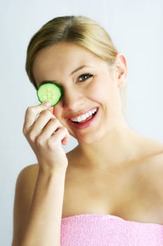 a young, beautiful, happy woman is holding some cucumber in front of her face