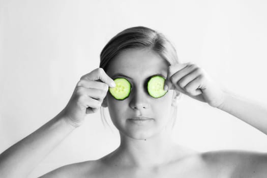 a young, beautiful, happy woman is holding some cucumber in front of her face