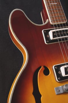 Close up of f hole and strings on an semi-hollow body electric guitar.
