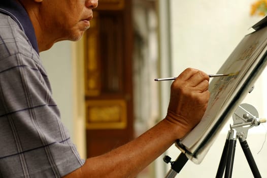 An asian chinese artist painting on street