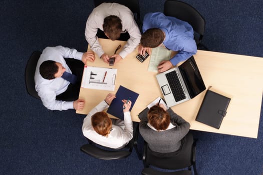 Businesspeople gathered around a table for a meeting, brainstorming. Aerial shot taken from directly above the table.