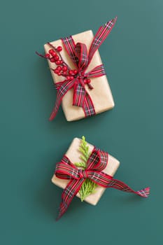Gift boxes wrapped in karft paper with red ribbon bow on green top view. Christmas or New Year Holiday atmosphere flat lay