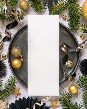 Black and golden Table setting with ornaments and fir tree branches, card mockup. Christmas or New Year menu on marble table flat lay, copy space. Winter season, restaurant holiday catering