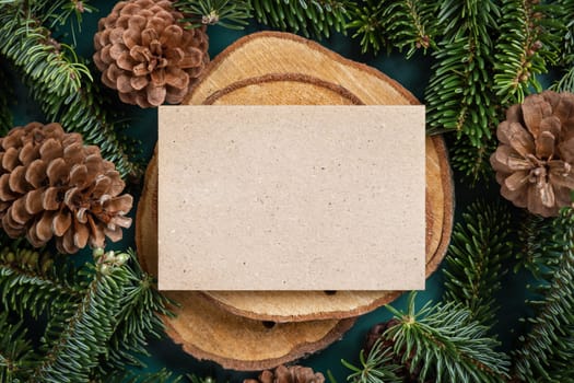 Horizontal blank card between fir branches and pine cones on green top view, mockup. Christmas or New Year greeting card template, Holiday winter composition