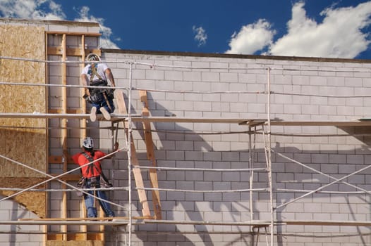 Carpenters working diligently along scaffolding one summer morning.