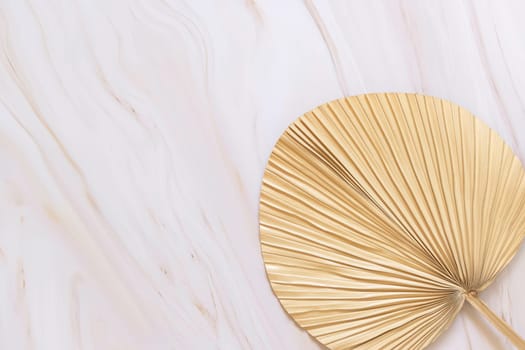 Dry beige palm leaf on marble table top view, natural bohemian bakground. Boho scene, minimal composition.