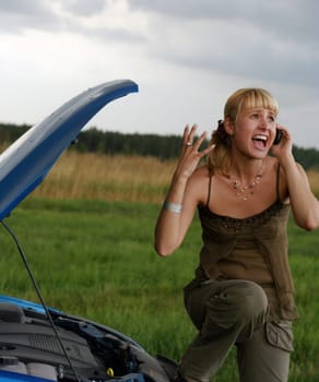 young blond woman with her broken car. The girl is sad
