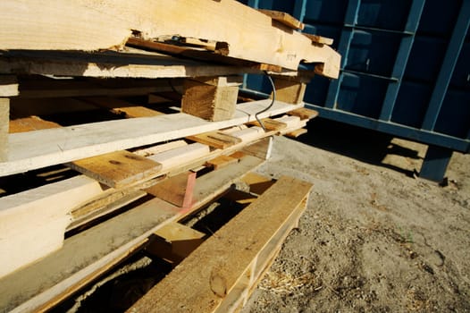 Abstract Stack of Wooden Palettes with Dumpster in the background.