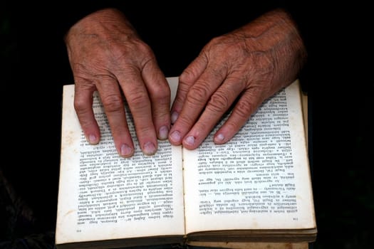 Senior's hands on old book