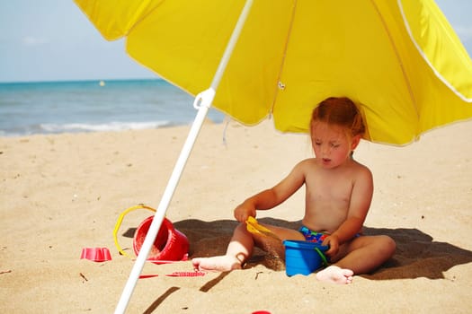 Cute kid playing with sand on a beach