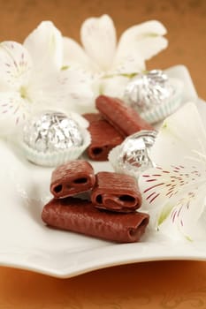 Sweet chocolate rolls on the plate decoraed with flowers