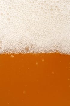 A macro image of a glass of amber beer.