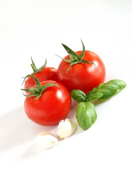 Close up of fresh tomatoes, basil and garlic, all on a white background