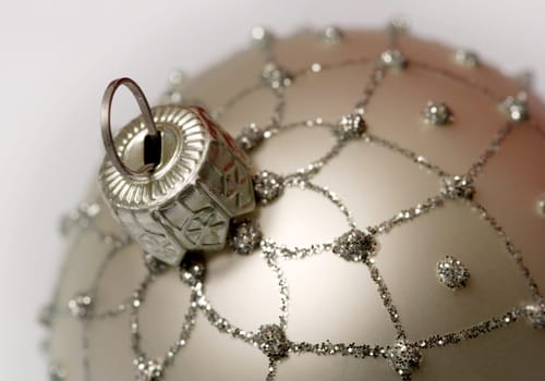 Macro image of a single silver Christmas ball.  Focus is on the hanger loop.