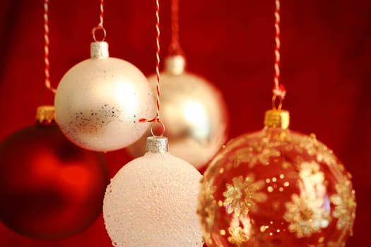 Various Christmas balls hanging with very shallow DOF and selective focus on the hanger of the middle ball.