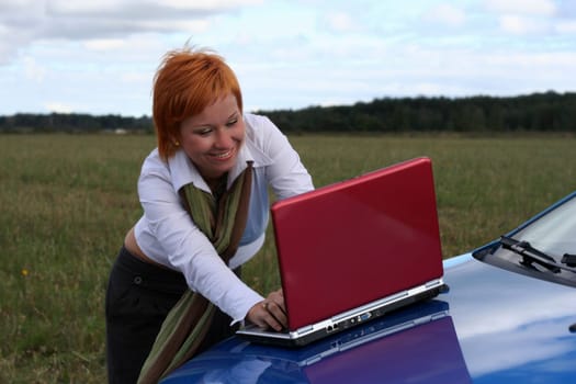young woman with red notebook on cowl of blue car
