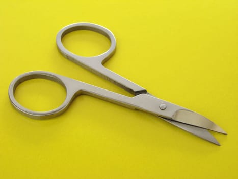 little manicure scissors on the yellow background