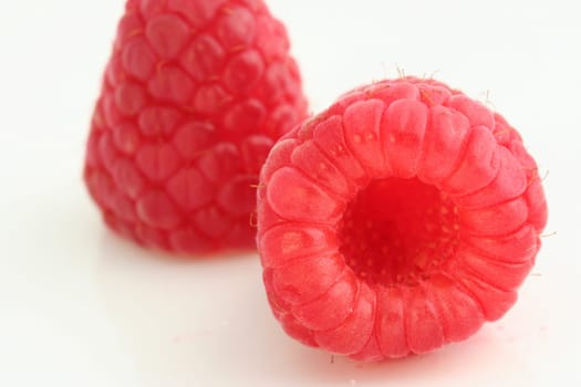 Two raspberries on white background