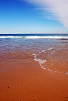 Sandy beach with blue ocean and blue sky