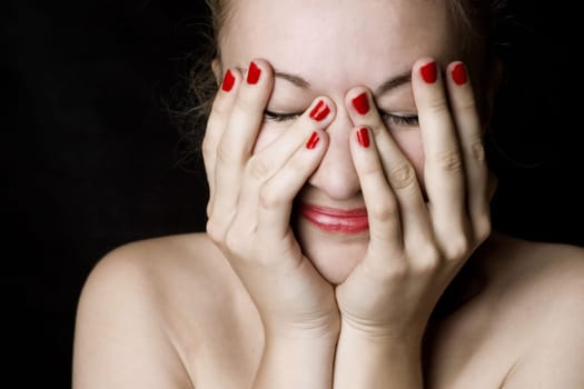 Beautiful smiling young woman with red lips and nails. Black background.