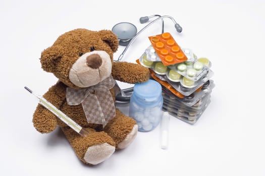 Teddy bear as a doctor with stethoscope and pills