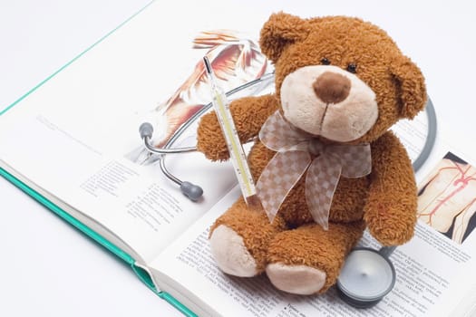 Teddy bear as a doctor with stethoscope on a medical book