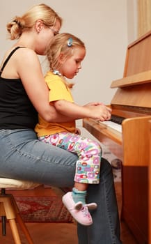 Mother and daughter play piano