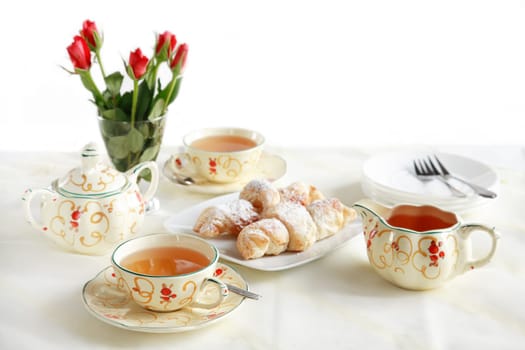 Two cups of tea with small sweet rolls