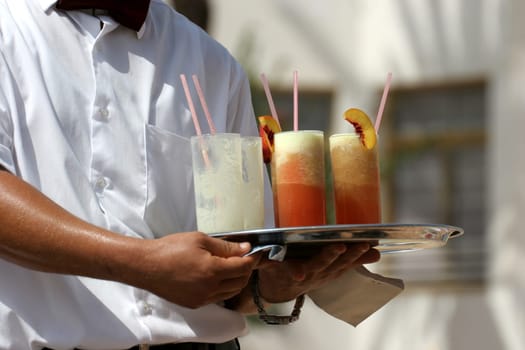 Waiter handling a salver with colorful cocktails.