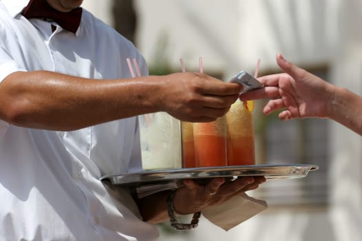 Waiter handling a salver with colorful cocktails.