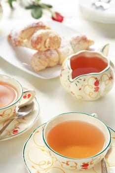 Two cups of tea with small sweet rolls