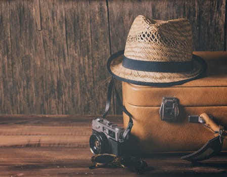 Vintage case, hipster hat,  and retro camera on wooden background still life.. Summer holiday vacation and adventure traveling concept.