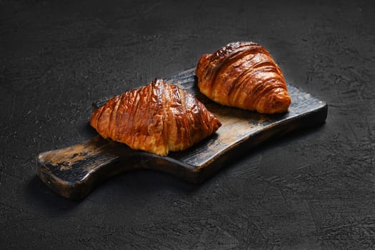 Crispy croissant on wooden serving board